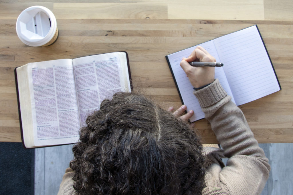 top view of woman journaling as she reads and works on a bible study