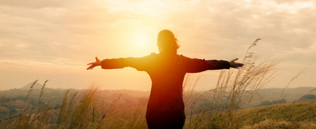 Woman standing in a field with arms outstretched 